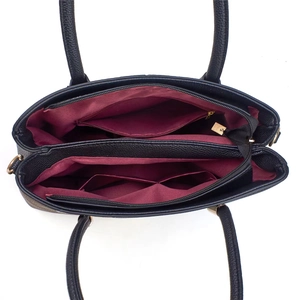 Detail view of the black handbag interior with burgundy lining and gold zippers