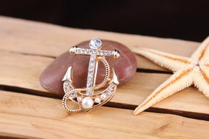 Close-up detail of the elegant anchor brooch featuring sparkling crystals and pearls.