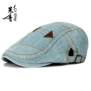 Side view of washed blue denim flat cap with brown stitching and adjustable metal buckle