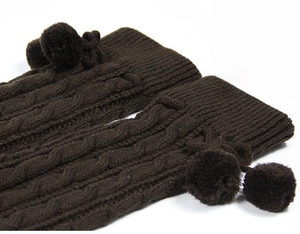 Detail showing dark brown cable knit texture and soft pom-poms on long leg warmers