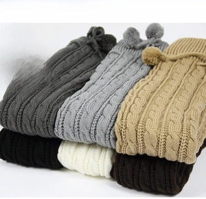 Detail showing cable knit patterns and pom-pom ties on long winter leg warmers in 6 colors