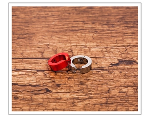 Macro shot of red and silver titanium steel clip-on earrings on a natural wood surface