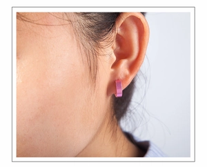 Close-up of pink matte titanium steel clip-on earring on model showing sleek C-shape
