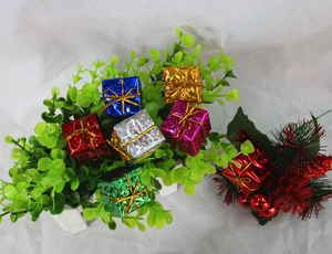 Close-up of colorful laser mini Christmas gift boxes hanging on decorative greenery
