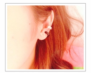Macro shot of silver and black clip-on earrings worn on the earlobe without piercings