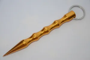 Macro detail of gold metal tactical kubotan keychain with non-slip grip for self-defense