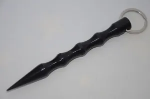 Close-up of black aluminum kubotan keychain with anti-slip grooves and a pointed tip