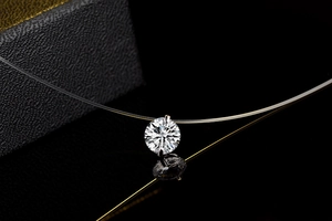 Macro shot of single round-cut zircon pendant with invisible fishing line on black mirror