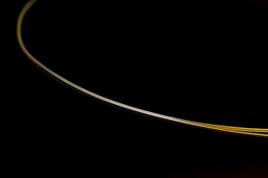 Macro detail of fine gold-colored thread with smooth texture on a black background