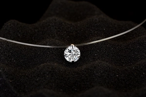 Macro detail of a single sparkling round cut zircon pendant on an invisible fishing line