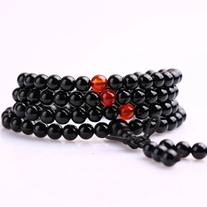 Detailed macro shot of black and red beaded multi-layer bracelet with cord tassels