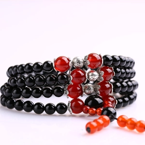 Detailed close-up of multilayer glass beaded bracelet with red tassels and silver spacers