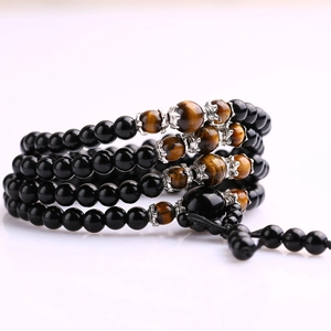 Detailed view of multi-layer obsidian and tiger eye bead bracelet with silver charms