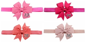 Detail of four colorful fishtail ribbon bows on elastic headbands for baby girls