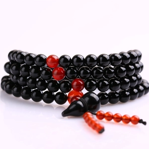 Detailed view of multi-layer beaded bracelet with black beads and red tassel accents