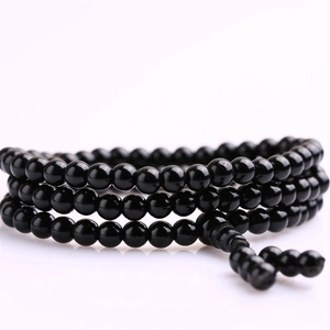 Detail of multi-wrap black glass bead bracelet with traditional woven knot and polished finish