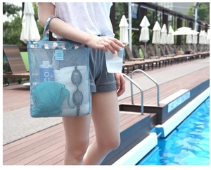 Blue mesh beach bag with floral patterns held by a model near a swimming pool