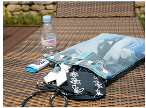 Close-up of light blue mesh beach bag with floral base on a woven bench for travel