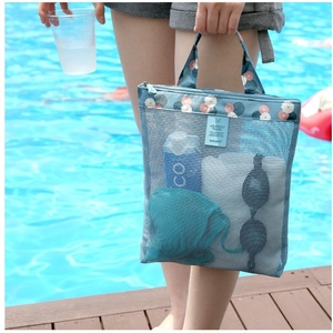 Detailed macro of small blue mesh beach bag with floral trim showing swim gear inside