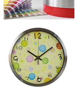 Detail of silver metal wall clock with colorful polka dot dial and bold black numbers