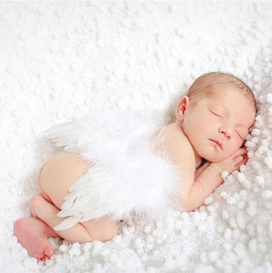 Macro shot of white feather angel wings on a sleeping newborn for professional photography