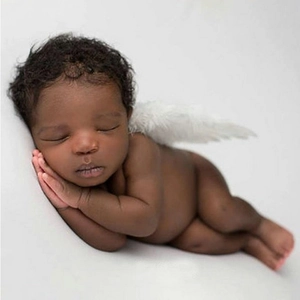 Detail of white feather angel wings prop on a sleeping newborn for baby photography