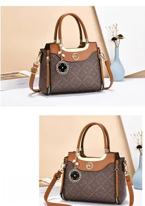 Detailed view of brown monogram handbag featuring gold hardware and clover charm