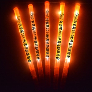 Close-up of vibrant orange LED glow sticks with custom text in low light background