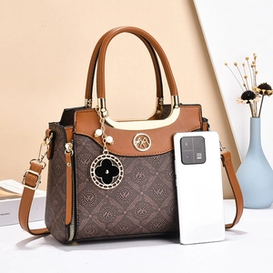 Brown monogram crossbody handbag with gold metal handles and a clover charm accessory