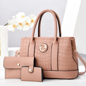 Pink crocodile-embossed handbag set with tote, wallet and coin purse in minimalist studio setting