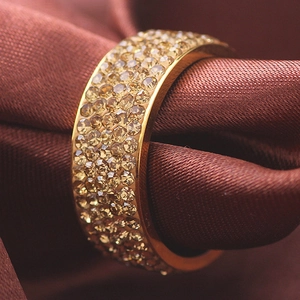 Close-up of gold stainless steel ring with multiple rows of champagne zircons on silk