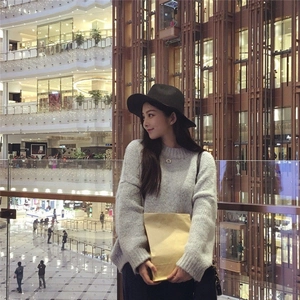Side view of model wearing a classic black wide-brimmed wool fedora hat with a grey sweater
