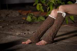 Close-up of brown knit leg warmers featuring delicate white lace trim and two buttons