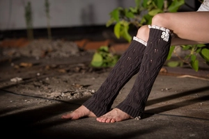 Detail of dark brown knitted leg warmer with white lace trim and double buttons