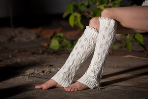 Detail of cream knitted leg warmers with delicate lace trim and decorative buttons