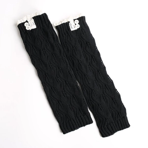 Close-up of black knitted leg warmers with white lace trim and decorative white buttons