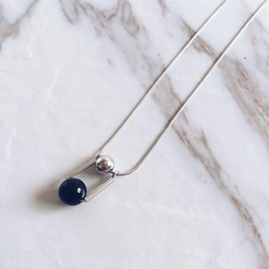 Macro shot of 925 sterling silver necklace with black agate bead on marble background