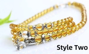 Macro shot of yellow beaded bracelet featuring vintage silver floral spacers and charms
