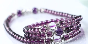 Macro detail of multilayer purple glass beaded bracelet with silver metal charms and clear beads
