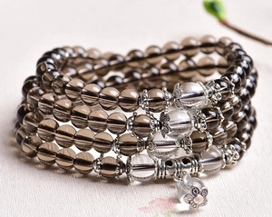 Macro shot of multi-layer beaded bracelet with brown glass beads and silver flower charm