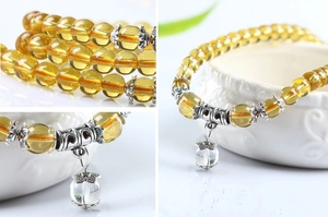 Detailed macro views of yellow beaded glass bracelet with clear teardrop pendant accessory