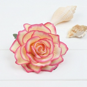 Close-up of cream artificial rose flower hair clip with pink edges on white wood background