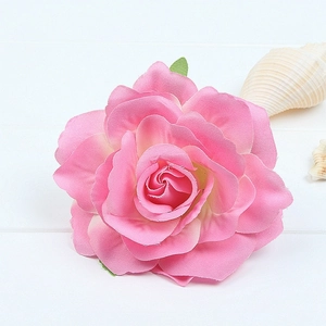 Detailed close-up of a pink artificial rose hair clip on a white wooden background
