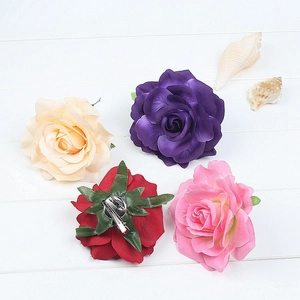 Detail of red rose hair clip with metal duckbill clip and pin on white wooden background