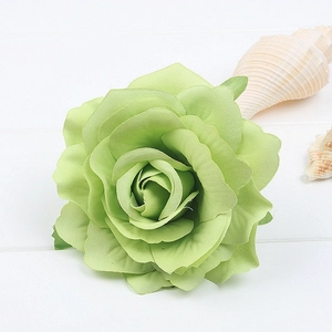 Detail of light green silk rose hair clip on white wooden surface with seashells