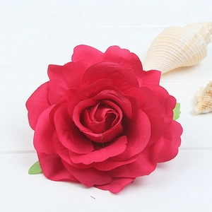 Macro shot of red silk rose hair clip petals with realistic texture on a white wooden background