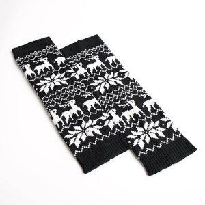 Detailed view of knitted leg warmers with reindeer and snowflake patterns in black and white