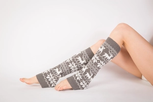 Detailed knit texture showing reindeer and snowflake patterns on grey leg warmers