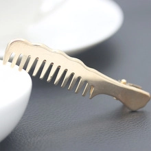 Macro view of a unique golden comb-shaped alloy hair clip resting on a white ceramic cup