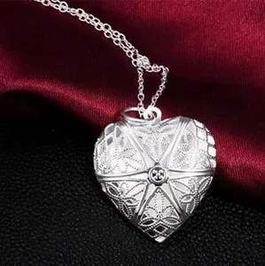 Close-up of a silver vintage hollow heart pendant with intricate floral engravings